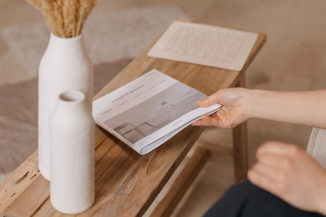 Scandinavian design: Woman placing a booklet onto a wooden table next to two vases